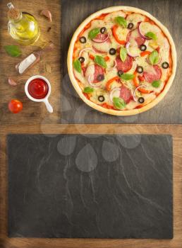 pizza and food ingredients at wooden table, top view