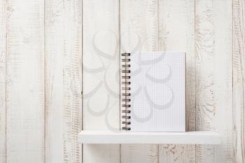 checked notebook on white wooden shelf