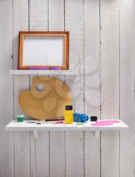 picture frame and paints on wooden shelf background