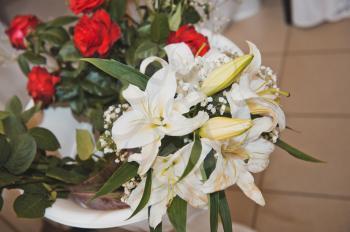 On a table bouquets from roses and lilies lie.