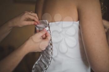 The girlfriend of the bride helps to dress a wedding dress.
