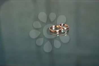 Two gold rings on a glass table.
