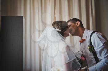 The groom takes the bride with veil and kisses her.