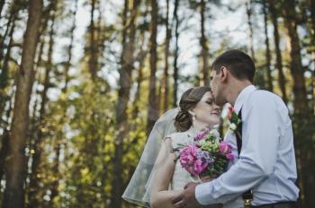 Newlyweds hugging on the background of the forest.