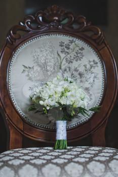 Beautiful upholstered chair with a bouquet on it.