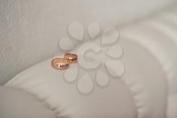 Wedding rings lie on a back of a white sofa.