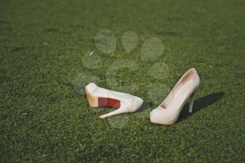 White shoes lie on a short-haired green lawn.