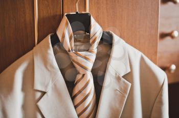 The man's suit and tie hangs on a hanger.