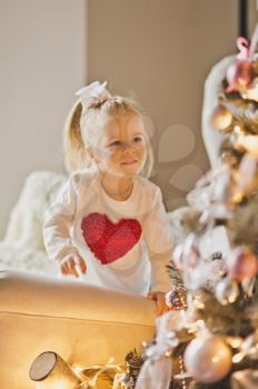 Baby playing with decorations on a Christmas tree.