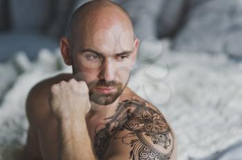Brutal man with tattoo on shoulder and chest.