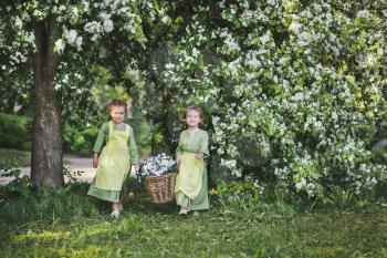 Two girls carrying a basket of flowers.