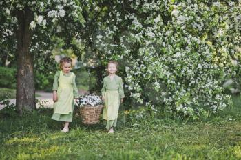 Two girls carrying a basket of flowers.