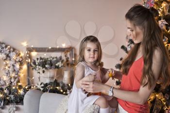 Mother and daughter on the background of sparkling Christmas garlands.