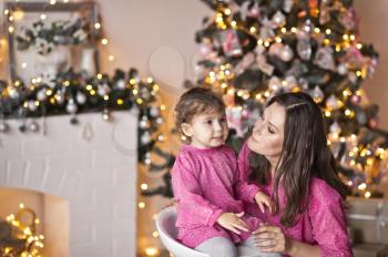 The little girl next to her mother, surrounded by Christmas light.