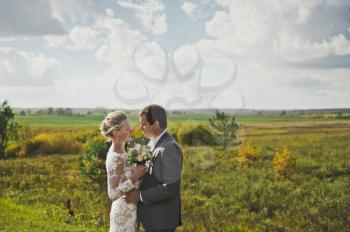 The bride and groom on the background of wide green fields.