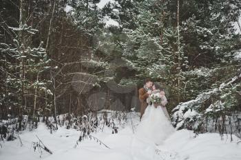 Beautiful portrait of bride and groom on winter forest background.