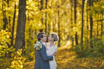 The bride and groom on the background of the brightly lit Golden autumn forest.