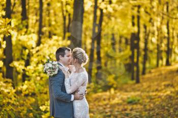 The bride and groom on the background of the brightly lit Golden autumn forest.