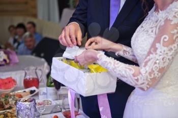 The groom helps the bride to open the gift.