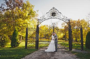 Portrait of the newlyweds standing near the beautiful wrought-iron gates.