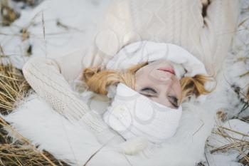 Portrait of girl lying on snow covered dry grass.