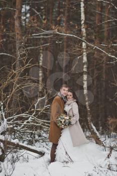 Portrait of the newlyweds in the background overgrown dark winter forest.