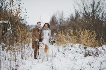 Portrait of newlyweds in winter for a walk with a dog.