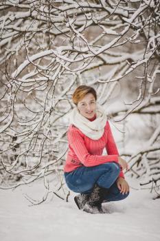 Portrait of a girl in a pink sweater on the background of snowy trees.