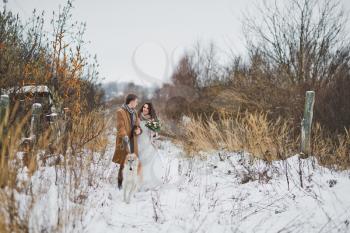 The bride and groom on a winter walk with a Russian Greyhound on a leash.