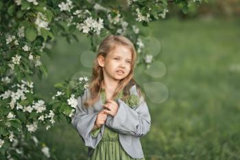 The child stands near a flowering cherry Bush.