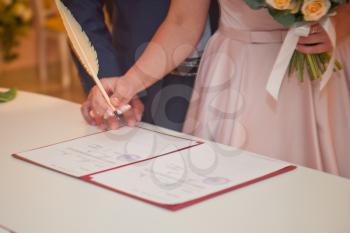 A woman signs a document with a pen.