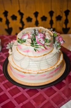 Three-tiered cake decorated with cream roses and leaves.