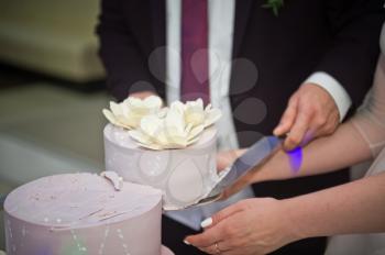 The process of cutting the wedding cake at the celebration.