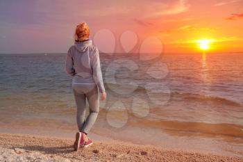 Girl stands with his back to the sea at sunset. Travel to Europe, Netherlands, North Sea near Amsterdam