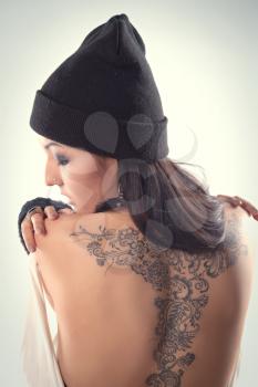 beautiful girl with a tattoo stands in the studio