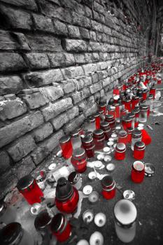 candle stand on the street near the wall. black and white photo with the color red