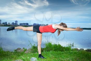 Girl athlete is pushed on one hand on a summer evening in the park by the river with views of the city. Lifestyle