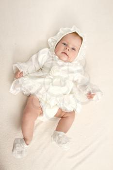 baby in a dress lying on the bed