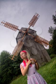 thoughtful young woman standing near a mill with a scarf