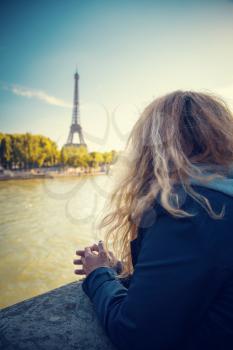 girl standing at the Hay River and looking at the Eiffel Tower. early autumn