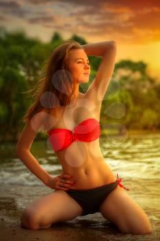 girl in a bathing suit on the beach in the water at sunset