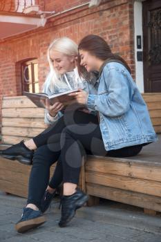 two friends reading a book on the street