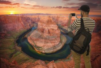 male tourist taking pictures of the Famous Horseshoe Bend of the Colorado River. Arizona
