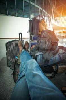 man who has a lot of bags, sits waiting for an airplane at the airport