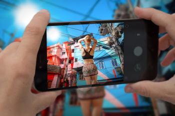   videobloger takes pictures on a smartphone. Colorful painted buildings of Favela  in Rio de Janeiro Brazil