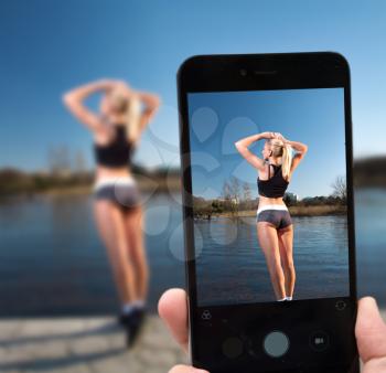 photograph a sportswoman model on a smartphone on the background of a river