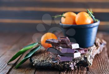 chocolate and tangerines on the wooden board and on a table
