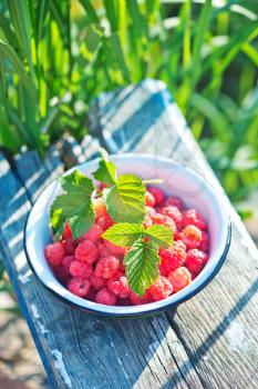 fresh raspberry in the bowl and on a table