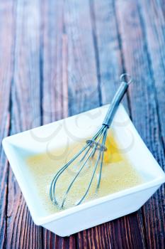 raw egg and whisk in white bowl