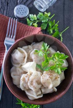 pelmeni in bowl and on a table